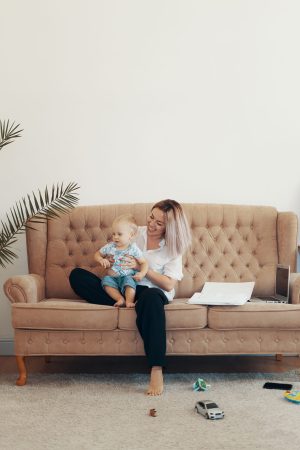 Young mother with her child working at home. Business mom takes a break. Multi-tasking, freelance and motherhood concept