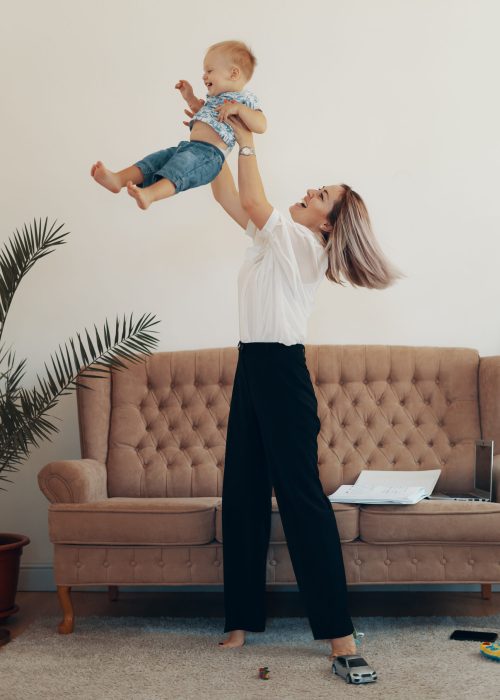 Young mother with her child working at home. Business mom takes a break. Multi-tasking, freelance and motherhood concept